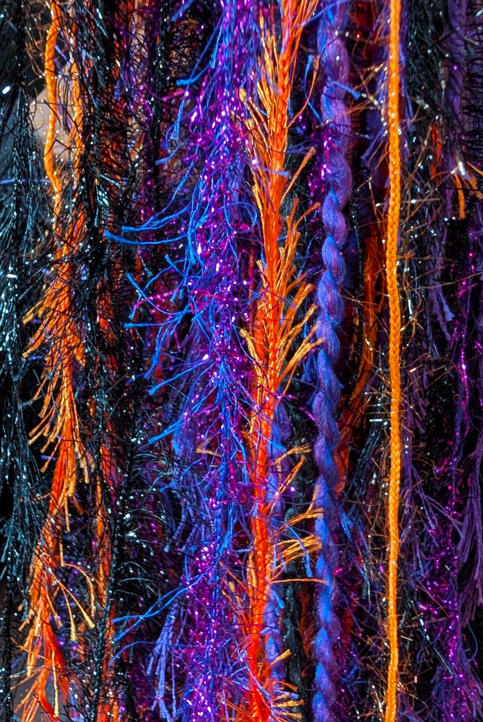 Black, Purple & Orange Halloween Slouchy Beanie Hat with Sparkle, Texture, Fur & Long Tail Fringe. Close-up View of Long Fringed Tail yarn varieties & textures.