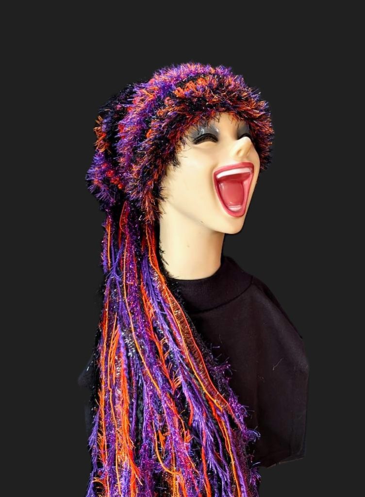 Black, Purple & Orange Halloween Slouchy Beanie Hat with Sparkle, Texture, Fur & Long Tail Fringe. Corner View of Head & Torso with Full Hat Length.